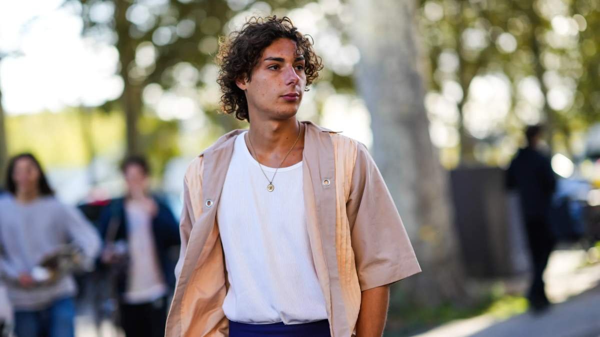 Joven usando collares para hombres en medio de la calle.